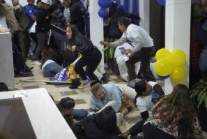 People take cover after shots were fired at the end of a rally of Ecuadorian presidential cadidate Fernando Villavicencio in Quito
