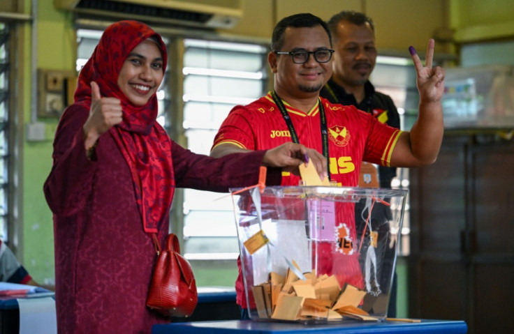 Selangor chief minister Amirudin Shari and his wife, Masdiana Muhamad, gesture before casting their votes in Saturday's state elections