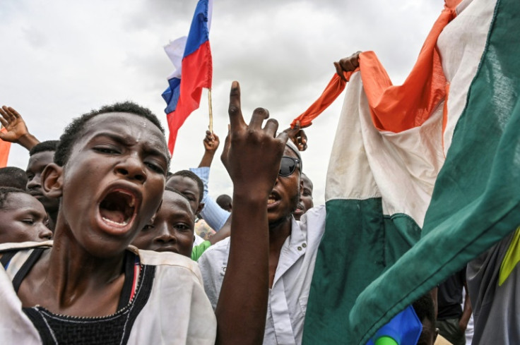 Coup supporters waving Russian and Nigerien flags at a demonstration outside a French airbase near Niamey on Friday. The base - adjoined to the international airport - is shared with Nigerien forces