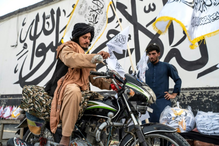 Vendors sell flags of the Islamic Emirate of Afghanistan -- the name given to the country by its new rulers -- in the capital Kabul ahead of the anniversary of the Taliban takeover