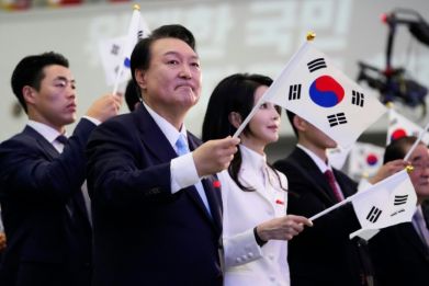 South Korean President Yoon Suk Yeol and wife Kim Keon Hee wave flags during a ceremony celebrating the 78th anniversary of the Korea's Japanese colonial rule