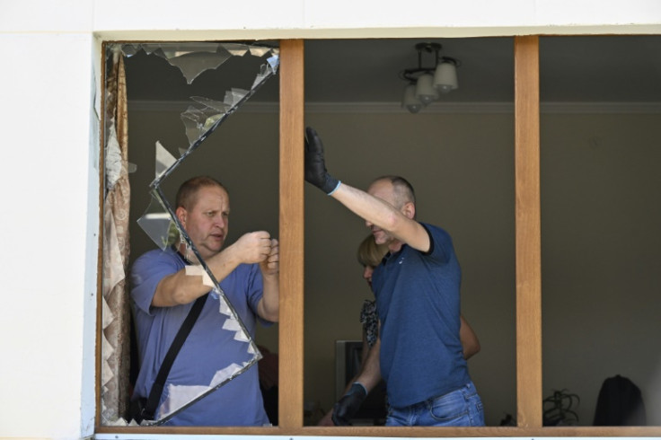 Local residents remove broken glass from the window of a residential building following a missile strike on the city of Lviv