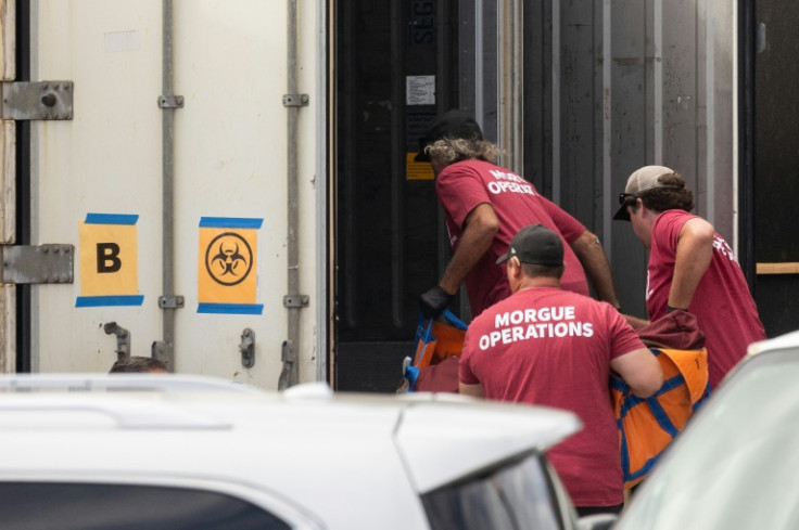 Morgue workers move a body bag into a refrigerated storage container adjacent to the Maui police department's forensic facility, where human remains are stored in the aftermath of the Maui wildfires