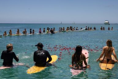 People throw flowers during a community paddle out for those affected by the Maui fires