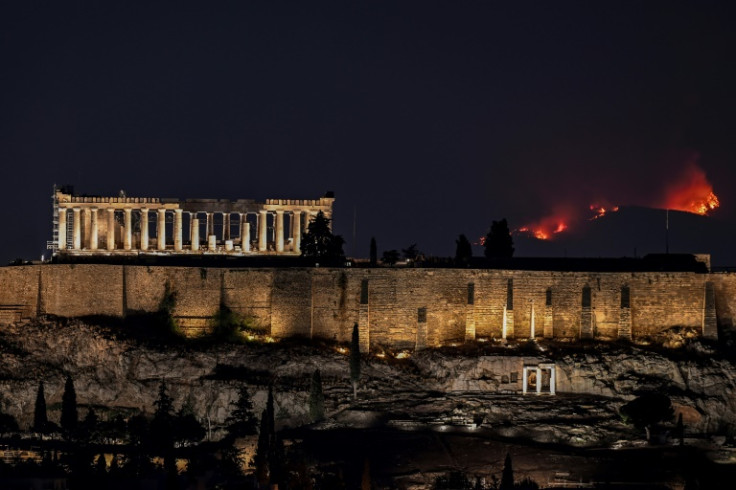 A forest burns behind the Parthenon ancient temple on top of the Acropolis hill as wildfire rages on the outskirts of Athens
