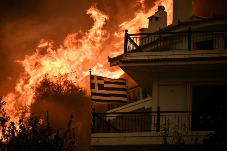 A Greek flag flutters in the wind during a wildfire in Chasia on the outskirts of Athens