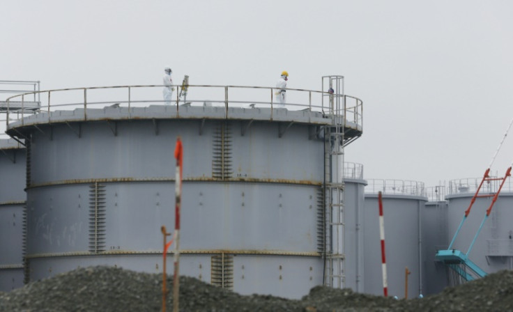 Workers wearing protective gear stand on a tank that stores radiation-contaminated water at Japan's Fukushima nuclear power plant in 2014