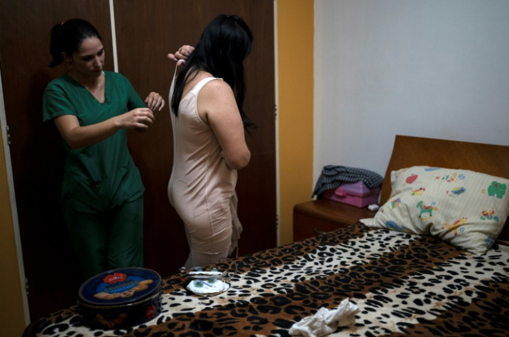 A nurse helps Maria Sanchez get dressed after her second operation to biopolymers from her buttocks