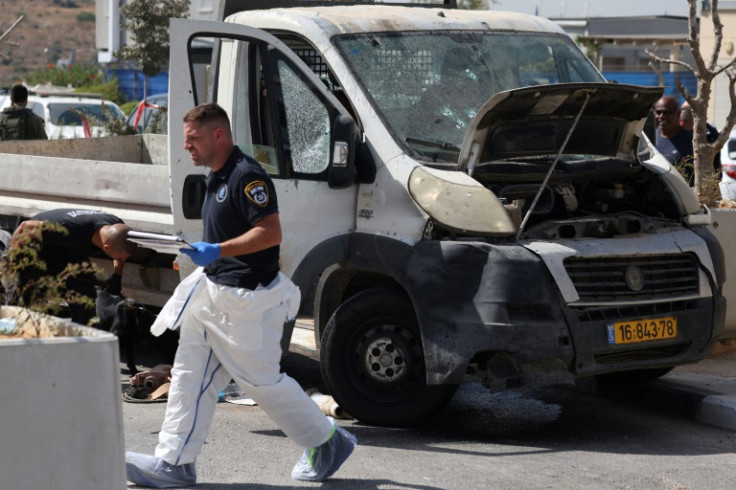 Israeli forensic officers inspect a bullet-riddled truck next to a checkpoint outside the Palestinian village of Nilin following a ramming attack
