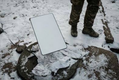 A Ukrainian serviceman stands next to the antenna of a Starlink satellite-based broadband system in Bakhmut in February 2023