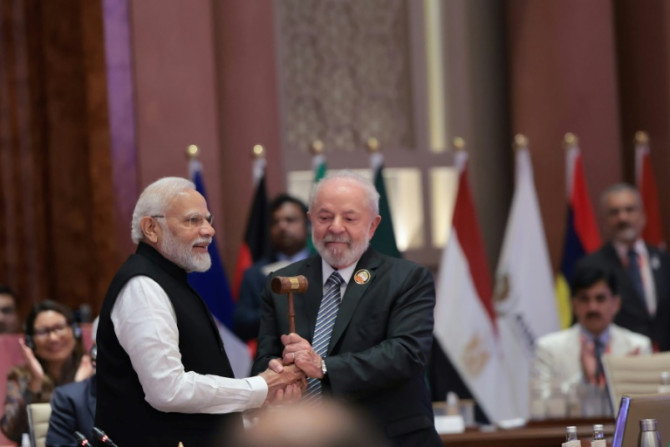 India's Prime Minister Narendra Modi (L) hands over the gavel to Brazil's President Luiz Inacio Lula da Silva (R) and the end of the G20 summit