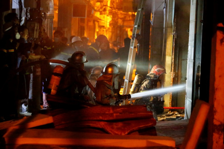Firefighters work to put out a fire and rescue people at an apartment block in Hanoi