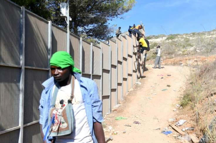 Migrants cross the fence to exit the operational centre