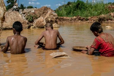 Venezuelan children work in a puddle of muddy water while searching for gold in an open-pit mine