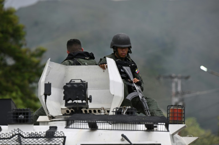 Members of the Bolivarian National Guard (GNB) sit on an armored vehicle in front of the Tocoron prison