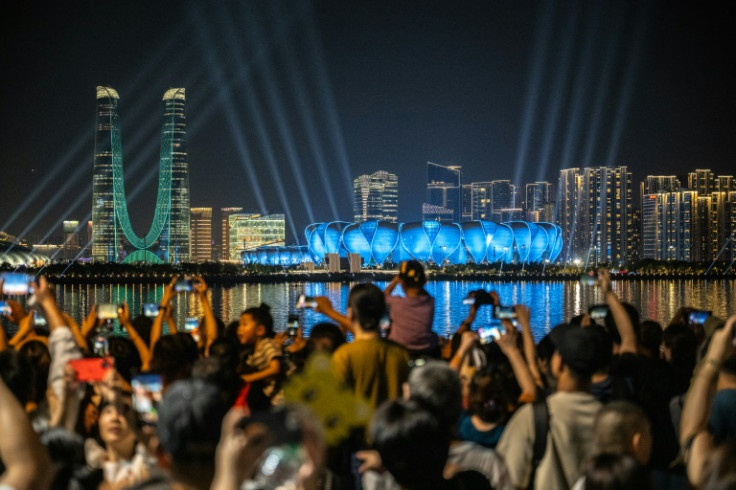 People gather to watch a light show from the Hangzhou Olympic Sports Centre Stadium