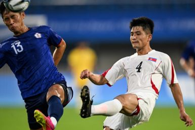 North Korea's Kim Pom Hyok (R) competes for the ball with Taiwan's Chen Po-yu at the Asian Games football