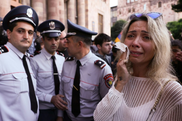 A woman cries next to Armenian police officers in front of the Government House during a demonstration in Yerevan