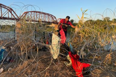 Venezuelan Alejandro Urdaneta makes his way through a tangle of barbed wire near the Texas town of Eagle Pass, one of hundreds of migrants to arrive in a single day