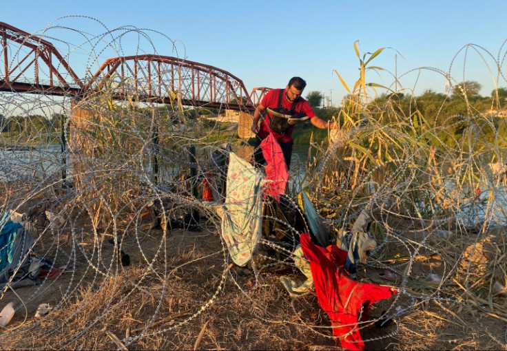 Venezuelan Alejandro Urdaneta makes his way through a tangle of barbed wire near the Texas town of Eagle Pass, one of hundreds of migrants to arrive in a single day