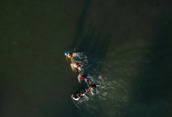 A family holds hands for support while crossing the Rio Grande to the United States on September 23, 2023