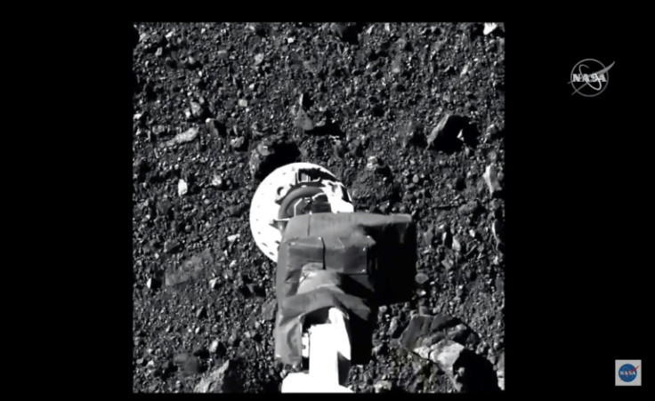 This image from a NASA video shows the robot arm of the Osiris-Rex probe collecting samples from the asteroid Bennu in October 2020