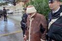 This handout video grab taken and released by the Italian Carabinieri Press Office on January 16, 2023 shows the transfer of mafia boss Matteo Messina Denaro (C) to an undisclosed location following his arrest