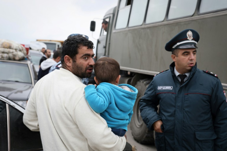 A refugee carrying a child, after crossing the border at a registration centre near the border town of Kornidzor