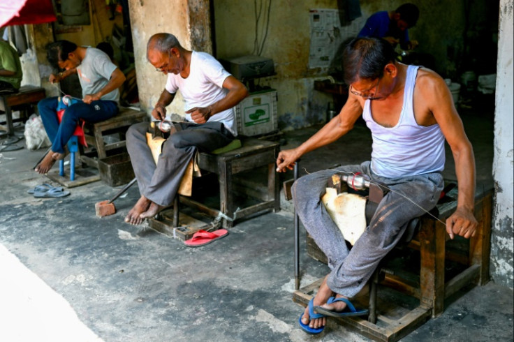 In this photograph taken on September 14, 2023, a worker polishes cricket balls at a workshop in Meerut in India's northern state of Uttar Pradesh