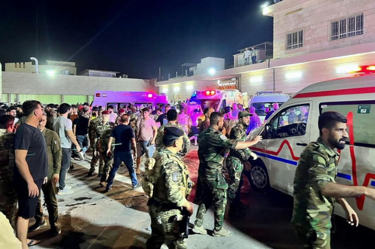 Soldiers and emergency responders gather around ambulances carrying people injured in a fire at an Iraqi wedding