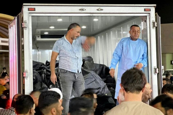 People gather outside a refrigerated truck carrying body bags at the hospital in Hamdaniyah