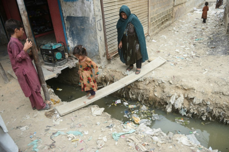 A girl and her mother cross a sewer line at an Afghan refugee camp in Karachi