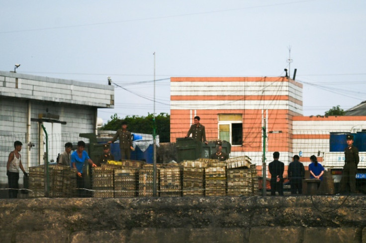 Soldiers and others working on a dock in the North Korean town of Sinuiju as seen from the border city of Dandong, in China