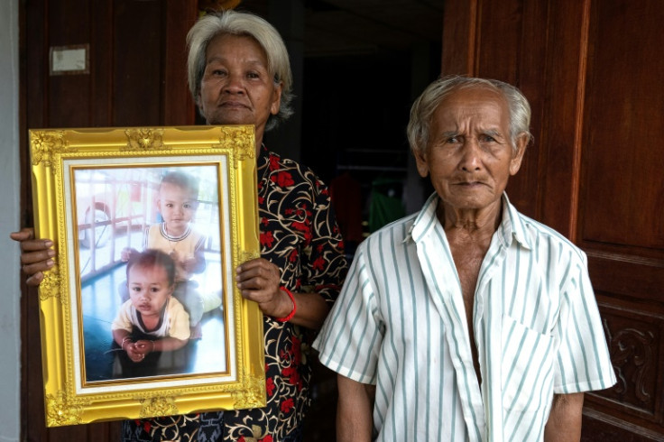 Pranee Tunawa standing beside his wife Thongsa Tunawa holding a photo of their three-year-old grandsons Aphiwut "Titan" Manochart and Chaiyanon "Asean" Thongpuban, who were killed in a nursery massacre in 2022