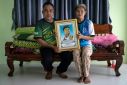 Kham Pornnikhom (L) and Banyen Srichanil hold a photo of their three-year-old grandson Nannaphat "Stamp" Songsermin, who was slaughtered in a mass killing at a nursery on October 6, 2022