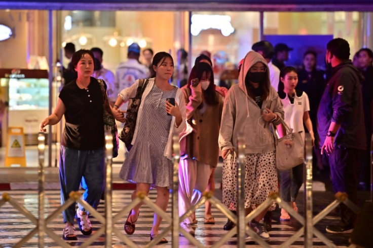 People leave Siam Paragon shopping centre after shots were fired inside the mall