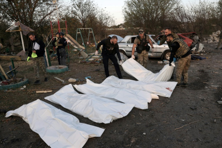 Ukrainian police carry bodies out of a destroyed shop and cafe after a Russian strike on the village of Groza
