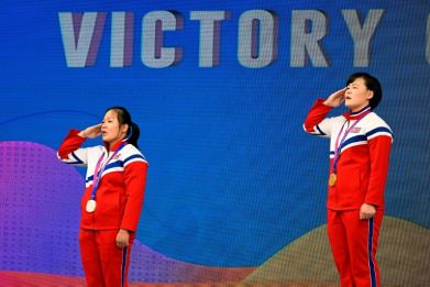 Strength and pride: North Korean gold medallist Song Kukh Yang (right) and silver medallist Jong Chun Hui salute during the medal ceremony of women's 76kg weightlifting competition