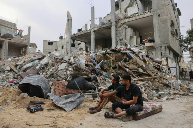 Young Palestinians sit in front of a levelled building following overnight Israeli air strikes on Rafah in the southern Gaza Strip, on October 9, 2023