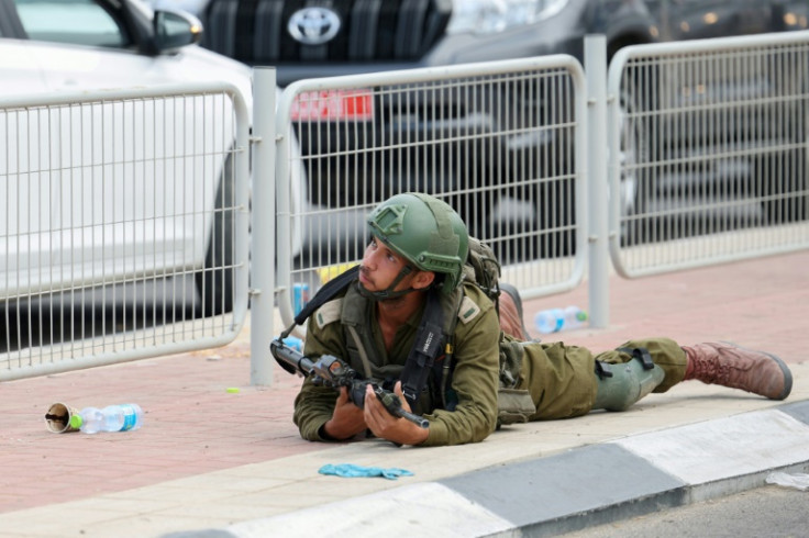 An Israeli soldier takes cover near Sderot on October 9, 2023, during a rocket attack from the Gaza Strip