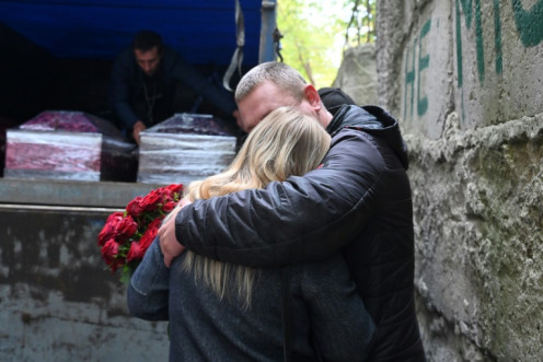 Grieving relatives await as coffins carrying victims of the the strike on Groza are made ready for collection  following forensic examination in Kharkiv