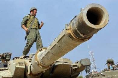 An Israeli soldier stands on the turret of a tank near the city of Sderot across the border with as Israel vows to destroy Hamas militants in the coastal enclave