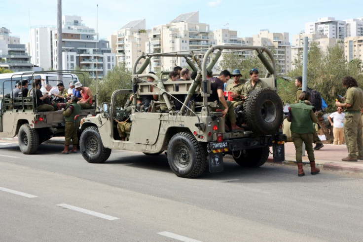 Israeli army reservists are transported in military vehicles to join their army base, south of Tel Aviv on October 7, 2023