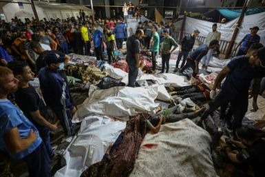 People gather around bodies of Palestinians killed in a strike on the Ahli Arab hospital in central Gaza after they were transported to Al-Shifa hospital, on October 17, 2023. A strike on a hospital compound in the Gaza Strip killed at least was blamed by