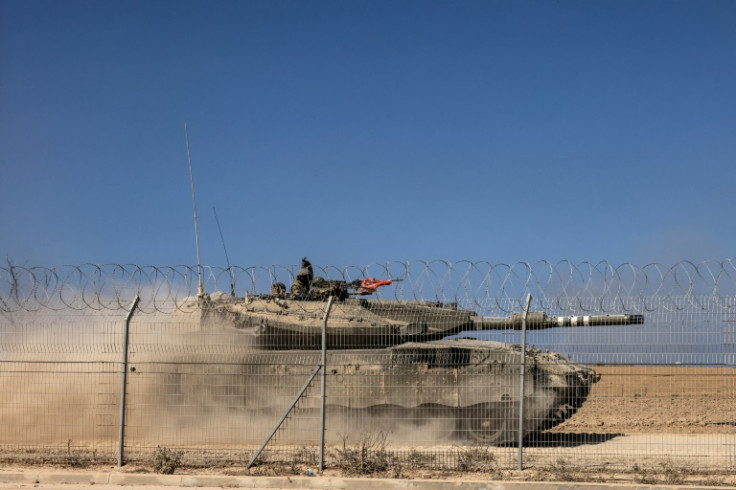 An Israeli Merkava tank drives past a fence near Kibbutz Beeri, close to the border with Gaza on October 20, 2023