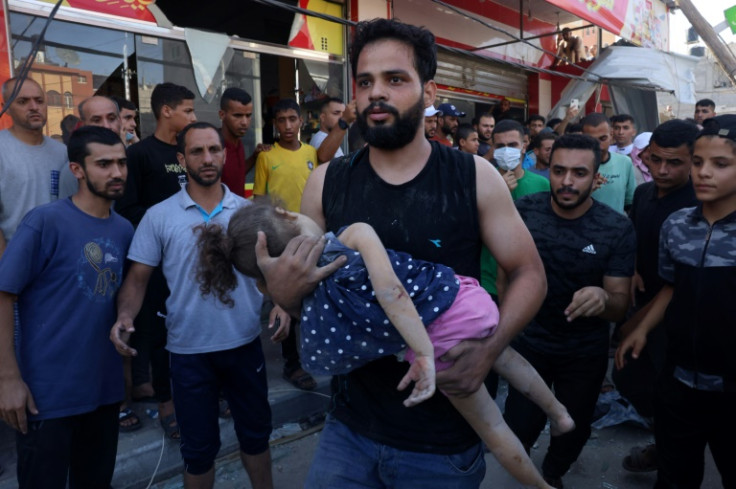 A man carries an injured girl after an Israeli strike on the Rafah refugee camp in the southern Gaza Strip on Wednesday. Israel's retaliatory bombardment of Gaza has killed over 6,500 people