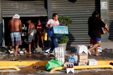 People carry groceries from a looted store in Mexico's hurricane-hit resort city of Acapulco