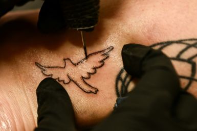 Tattoo artist Kat Dukes inks a hand poked tattoo of a dove on Scout Frank using ink mixed with the ashes of Frank’s cremated mother in Oceanside, California on October 6, 2023