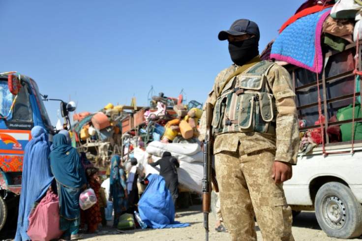 An Afghan police personnel stands guard as refugees arrive at the Afghanistan-Pakistan border in Spin Boldak