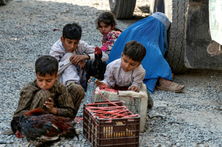 An Afghan refugee woman and children rest beside a truck on their arrival at the Torkham border